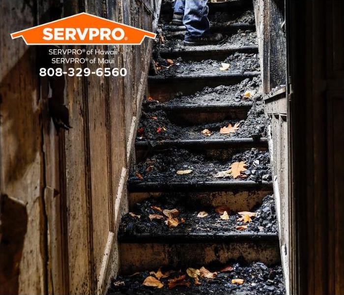 Stairs inside of a house are covered in soot and debris from a fire.