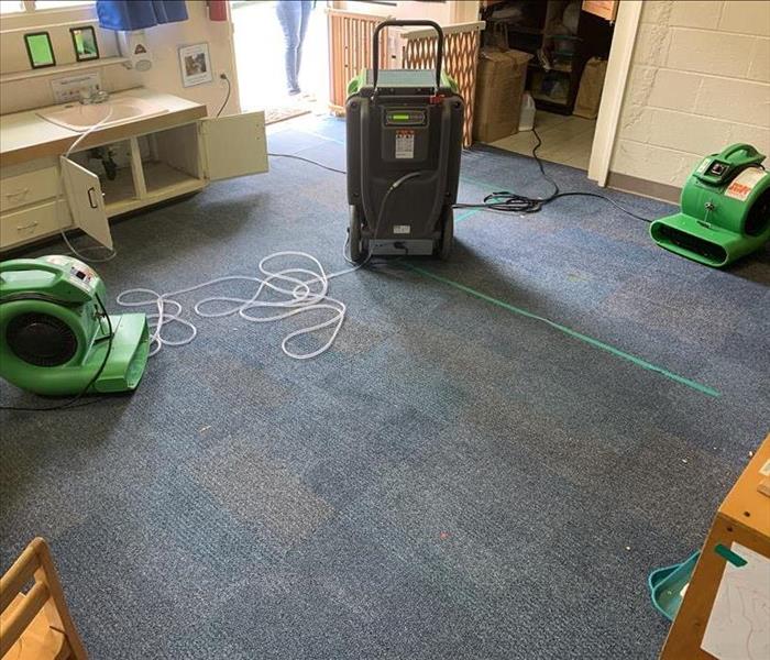 Classroom with air movers and a dehumidifier next to a small vanity