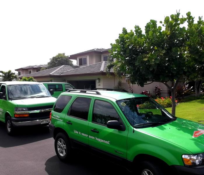 3 green SERVPRO vehicles parked outside a business
