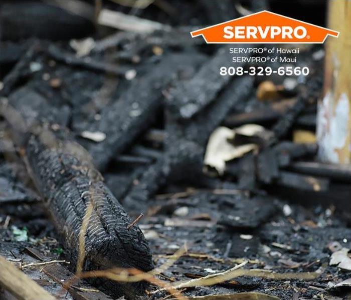 Fire debris, ashes, and soot cover the ground. 