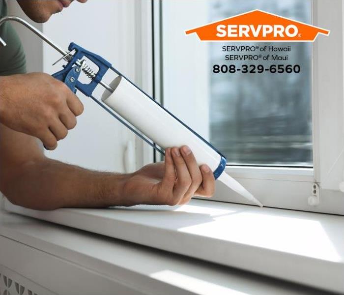 A person seals gaps around a window to prevent moisture entry into their home.