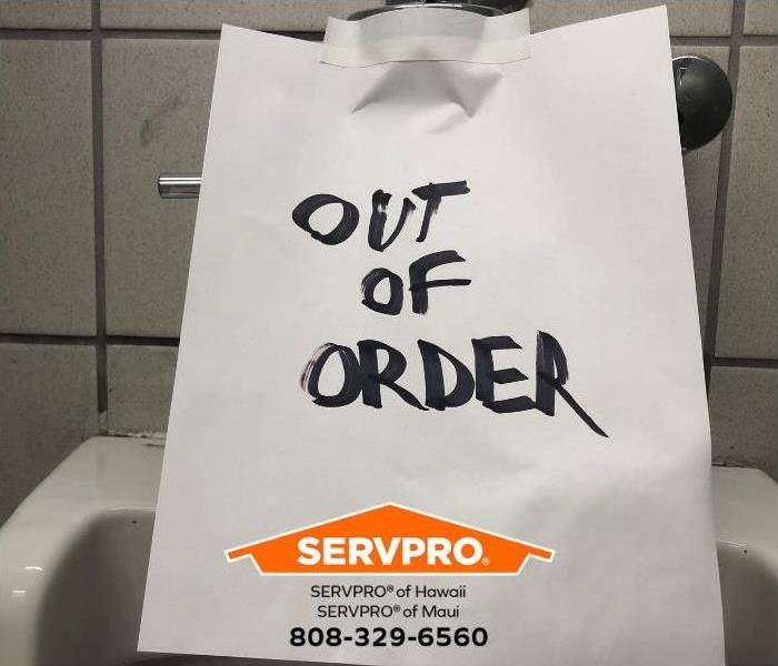 An out of order sign is taped to a toilet in a public restroom.